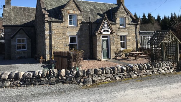A stone building with a traditional architectural style, featuring multiple chimneys and a prominent entrance with a sign. - The Struan Inn Self Catering Lodge (Pitlochry)