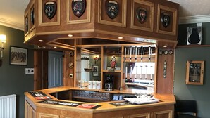 A bar area with wooden paneling, a coffee machine, and various bar tools. There are framed certificates on the wall and a mirror reflecting the bar area. - The Struan Inn Self Catering Lodge (Pitlochry)