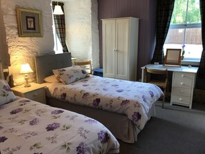 A bedroom with two beds, a wardrobe, a desk, and a window with curtains.