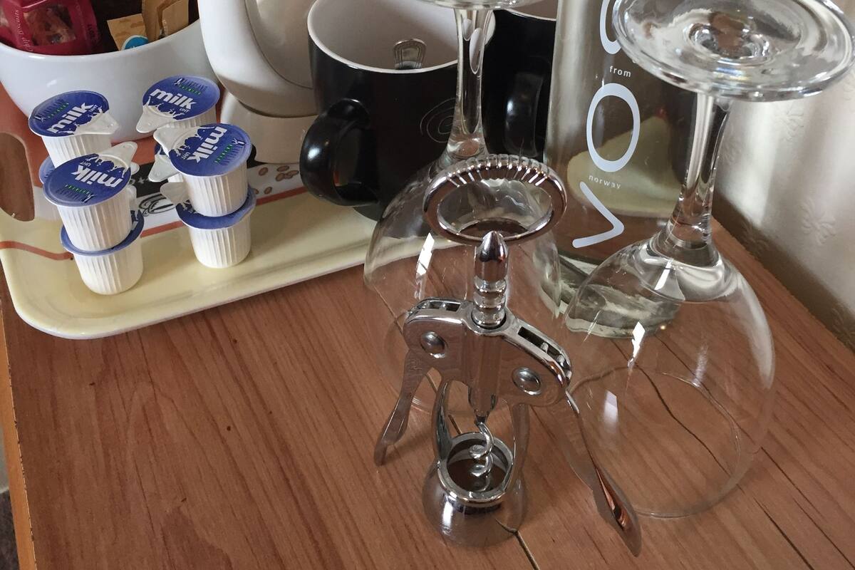 A coffee maker, a water dispenser, and a tray with milk cartons on a wooden table.