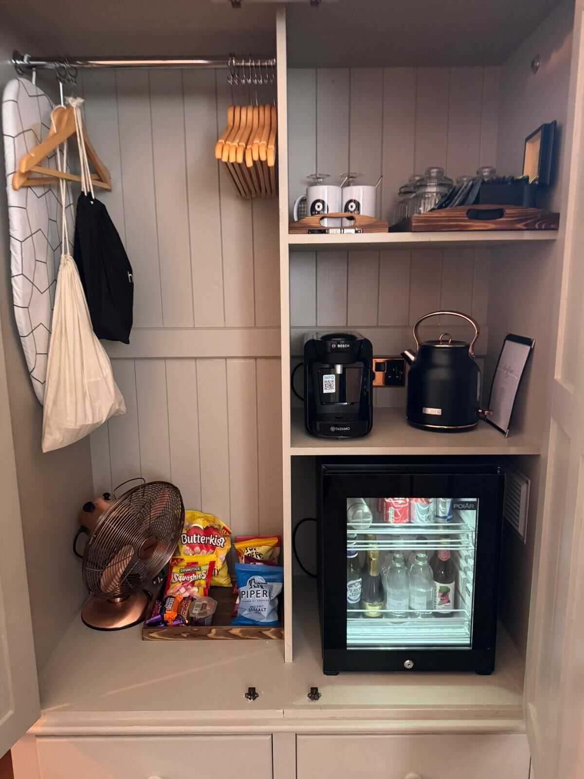 Una cocina compacta con una cafetera Bosch, un hervidor, un refrigerador pequeño y aperitivos.