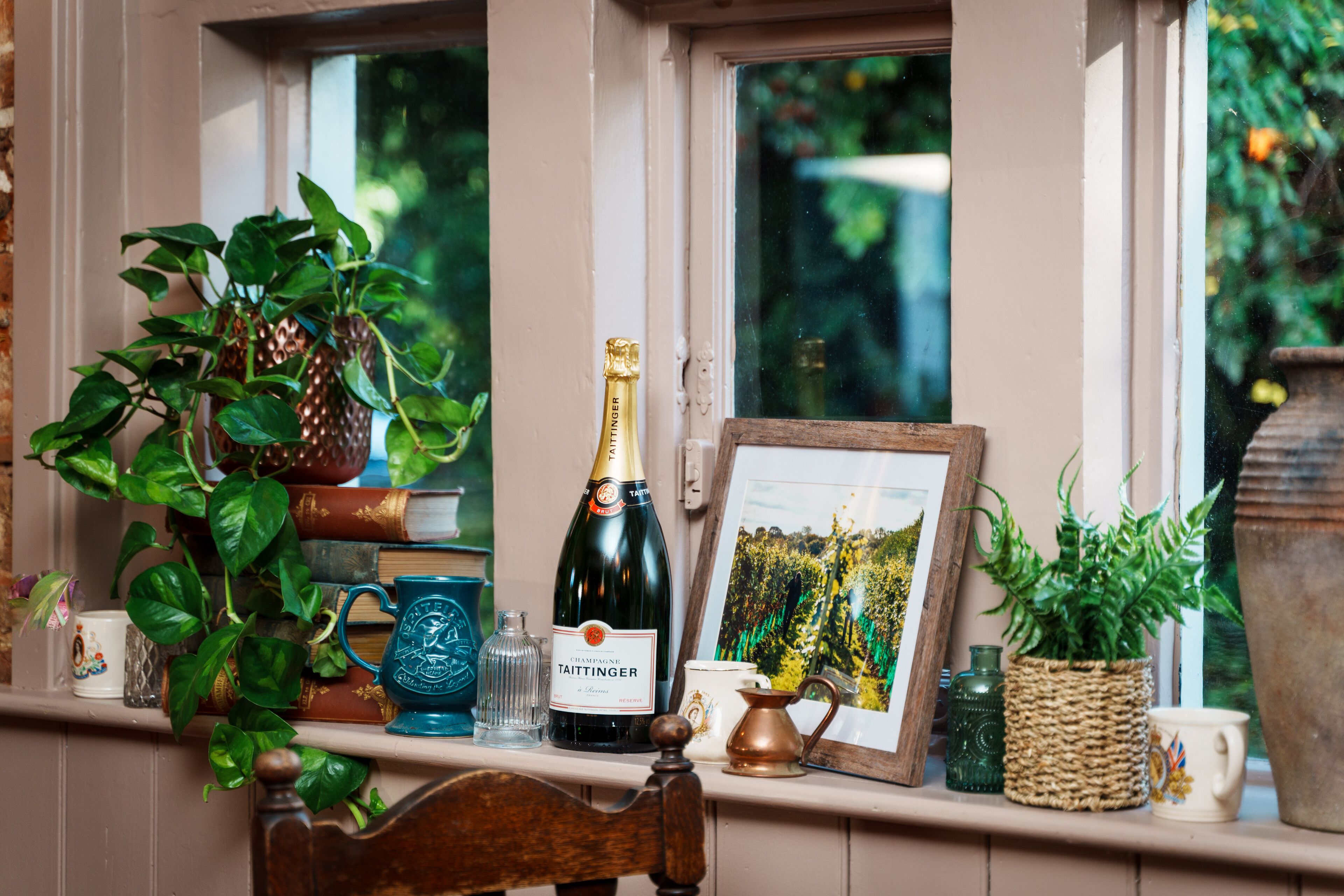 Une étagère avec une bouteille de champagne Taittinger, un tableau encadré et divers objets décoratifs.