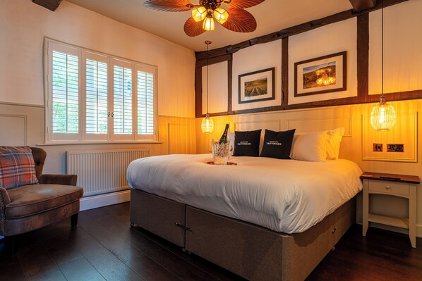 A bedroom with a large bed, a chair, a nightstand, and a ceiling fan.