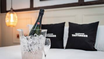 Un lit avec une bouteille de champagne dans un verre, des glaçons et une assiette. On peut voir deux oreillers portant le nom de la marque.