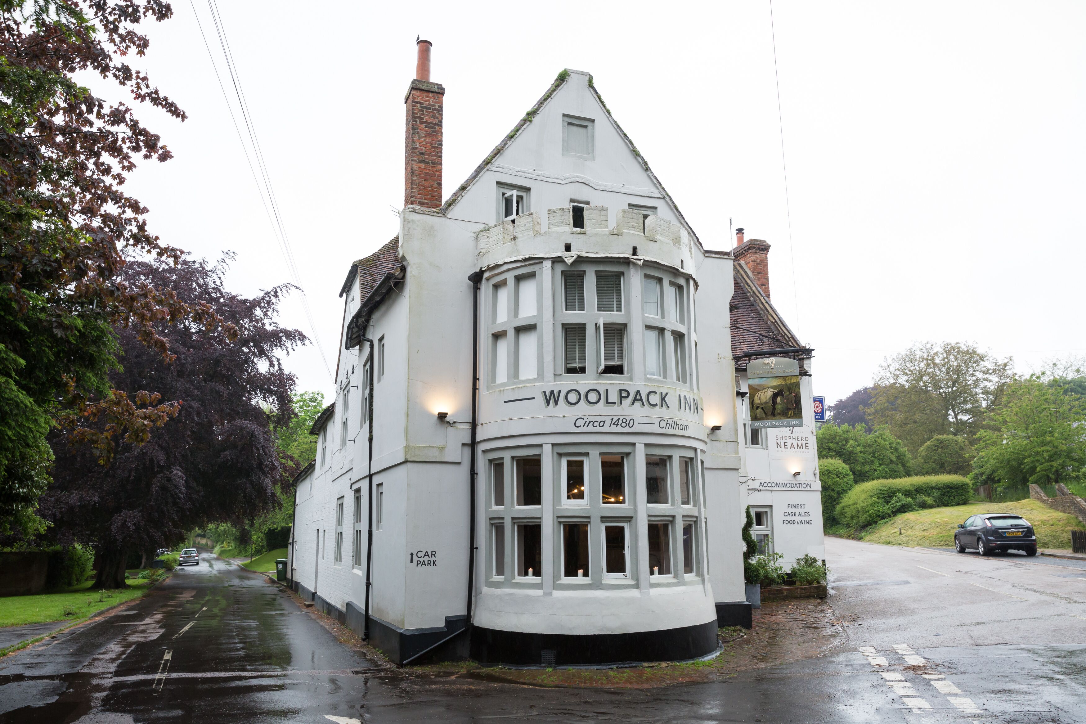 Un edificio blanco con un letrero que dice "WOOLPACK INN" y "Chillham".