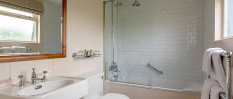 A bathroom with a white sink, toilet, and glass-enclosed shower.