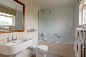 Un baño con lavamanos blanco, inodoro y ducha con mampara de vidrio.