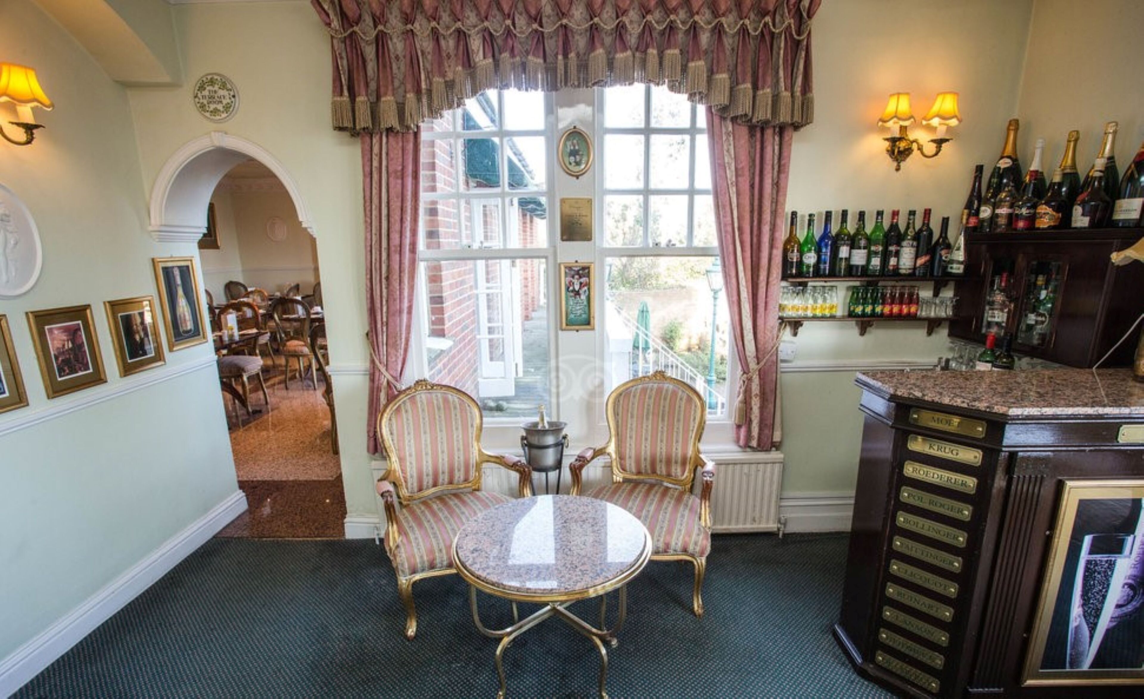A room with a dining area, a bar, and a view of the outside.