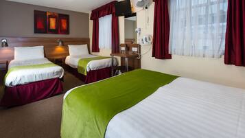 A hotel room with two single beds, a desk with a chair, a TV, and a window with curtains.