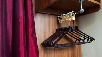 Un mur en bois sur lequel est fixé un porte-manteaux en bois, qui supporte plusieurs cintres de couleur foncée.