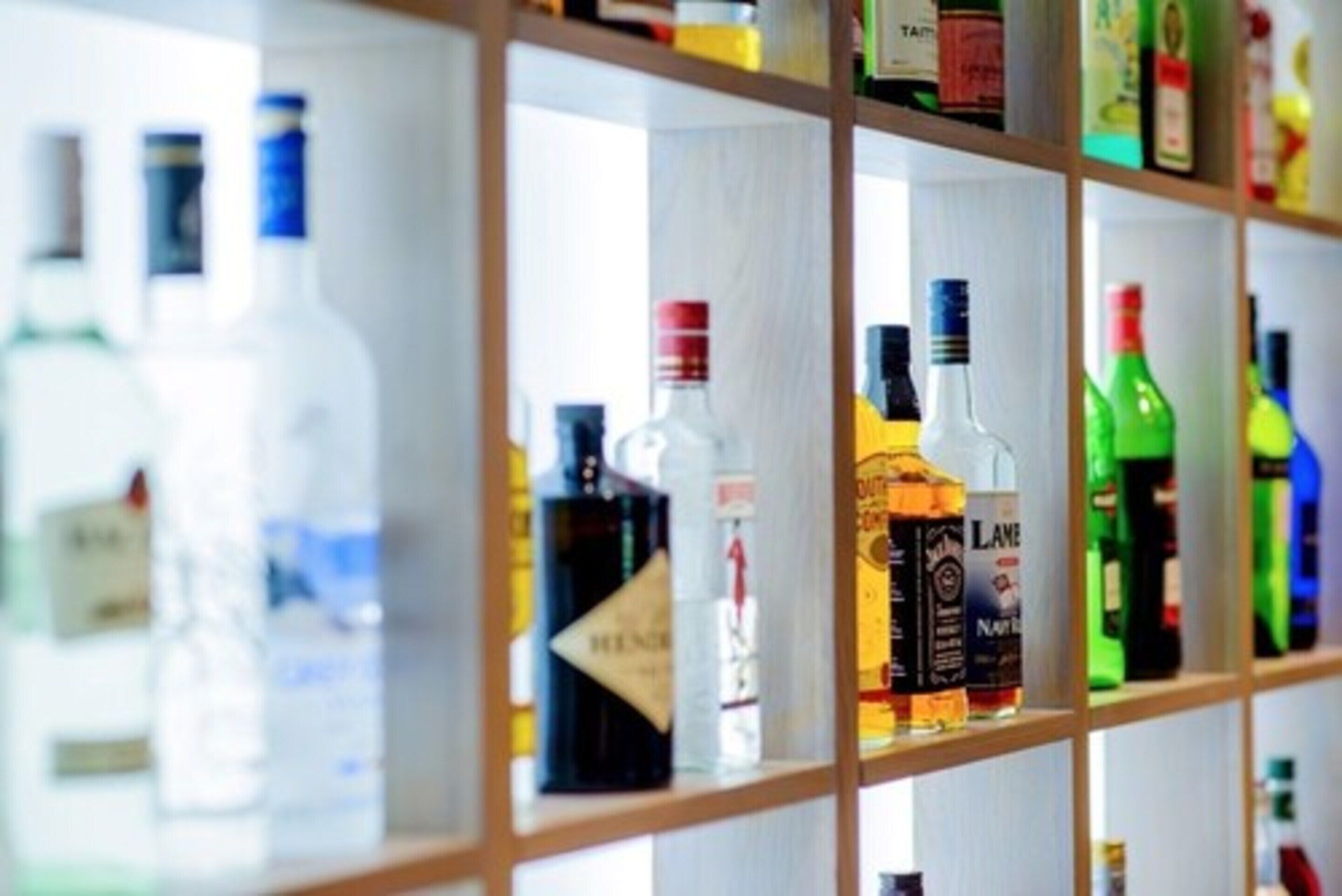 Uma prateleira com diversas garrafas de bebidas alcoólicas.