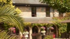 A garden with a building in the background. - Le Friquet Country Hotel (Castel)