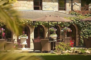 Un bâtiment en pierre doté d’une terrasse et de plantes en pot.