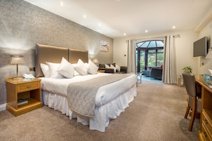 Un dormitorio amplio con una cama grande, un escritorio y vistas al exterior.