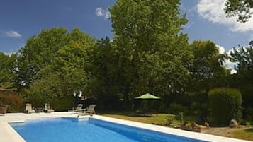 Een buitenzwembad, ligstoelen bij het zwembad