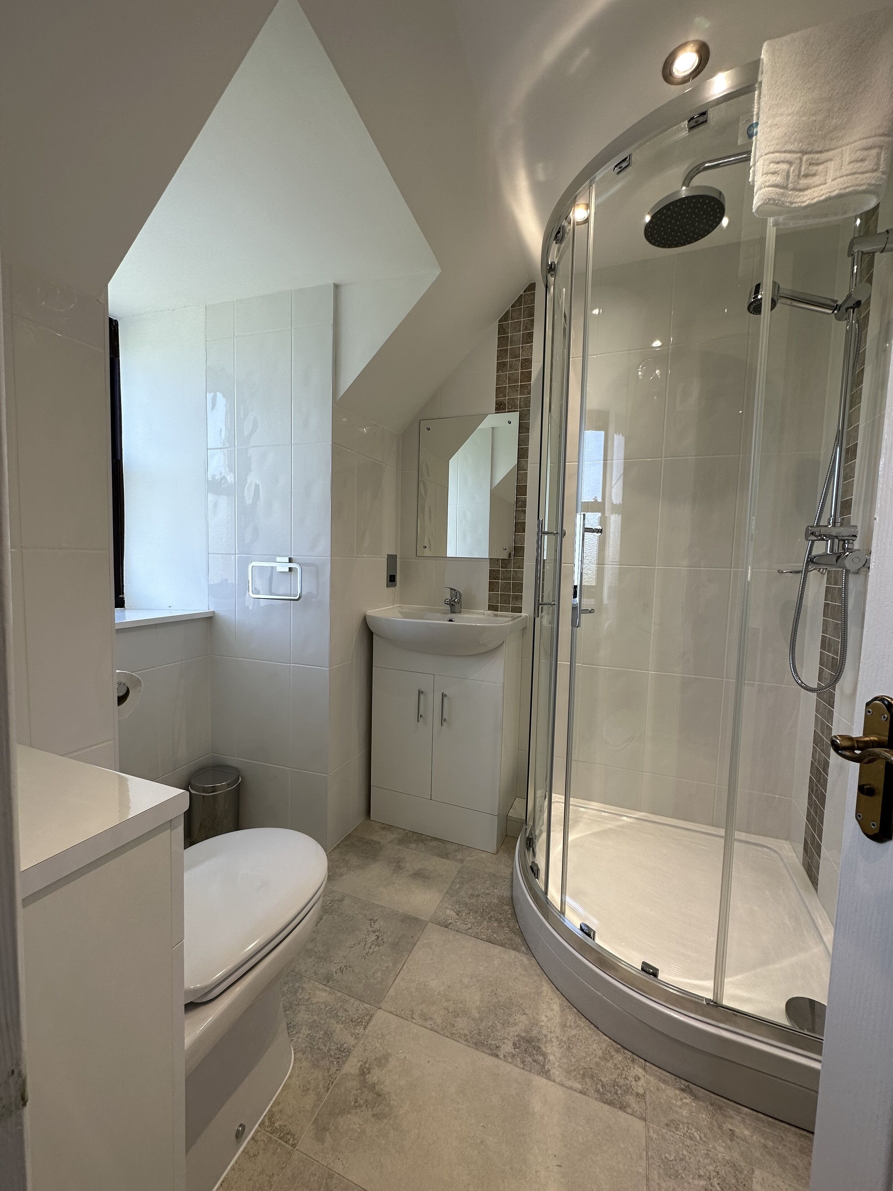A modern bathroom with a glass-enclosed shower, a white sink, and a toilet.