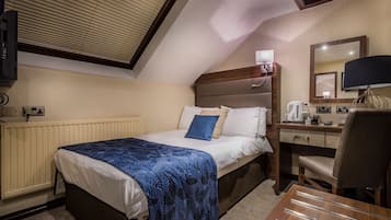 A hotel room with a bed, desk, chair, and a television mounted on the wall.
