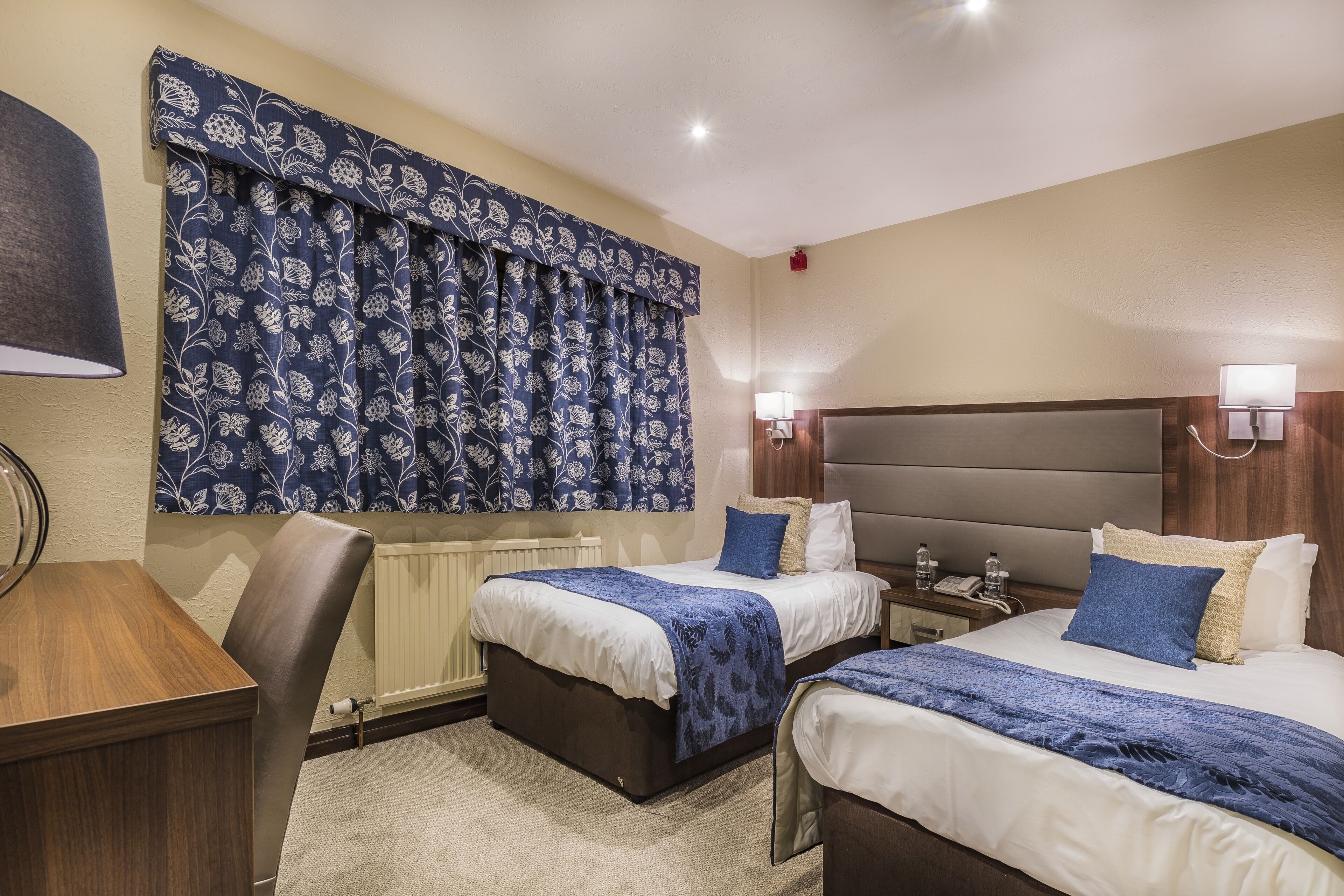 A hotel room with two beds, a desk, and a chair.