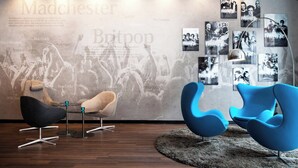 Un espace de détente moderne, avec des fauteuils contemporains, un mur décoré de posters de groupes de musique et un plancher en bois.