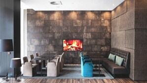Un espace de détente moderne avec un mur en pierre, une cheminée, des sièges et un téléviseur.