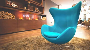 A modern living room with a teal armchair, a wooden entertainment unit, and a fireplace.