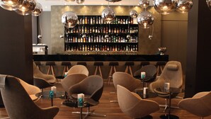 Un espace bar doté de tabourets de bar modernes et d’un mur où sont exposées des bouteilles d’alcool.