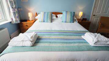 A neatly made bed with striped bedding and pillows, a bedside lamp, and a framed picture on the wall.