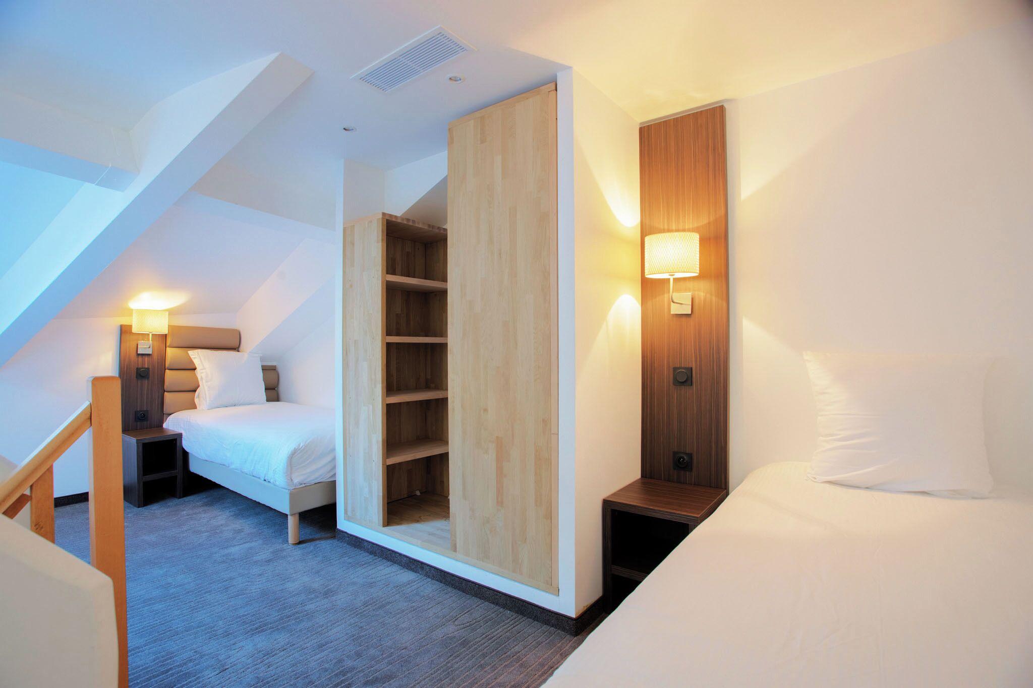 A modern bedroom with a loft-style bed, built-in wooden shelving, and a wall-mounted reading light.