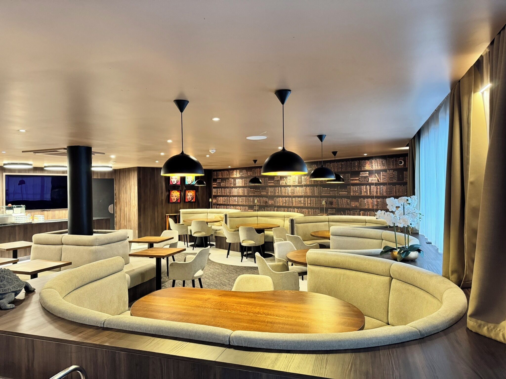 Un'area lounge moderna con divani, tavolini e lampade a sospensione.