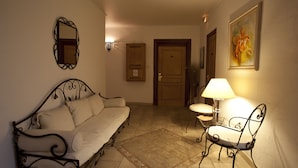 Une pièce confortable avec un canapé, un fauteuil, une lampe et un tableau au mur.