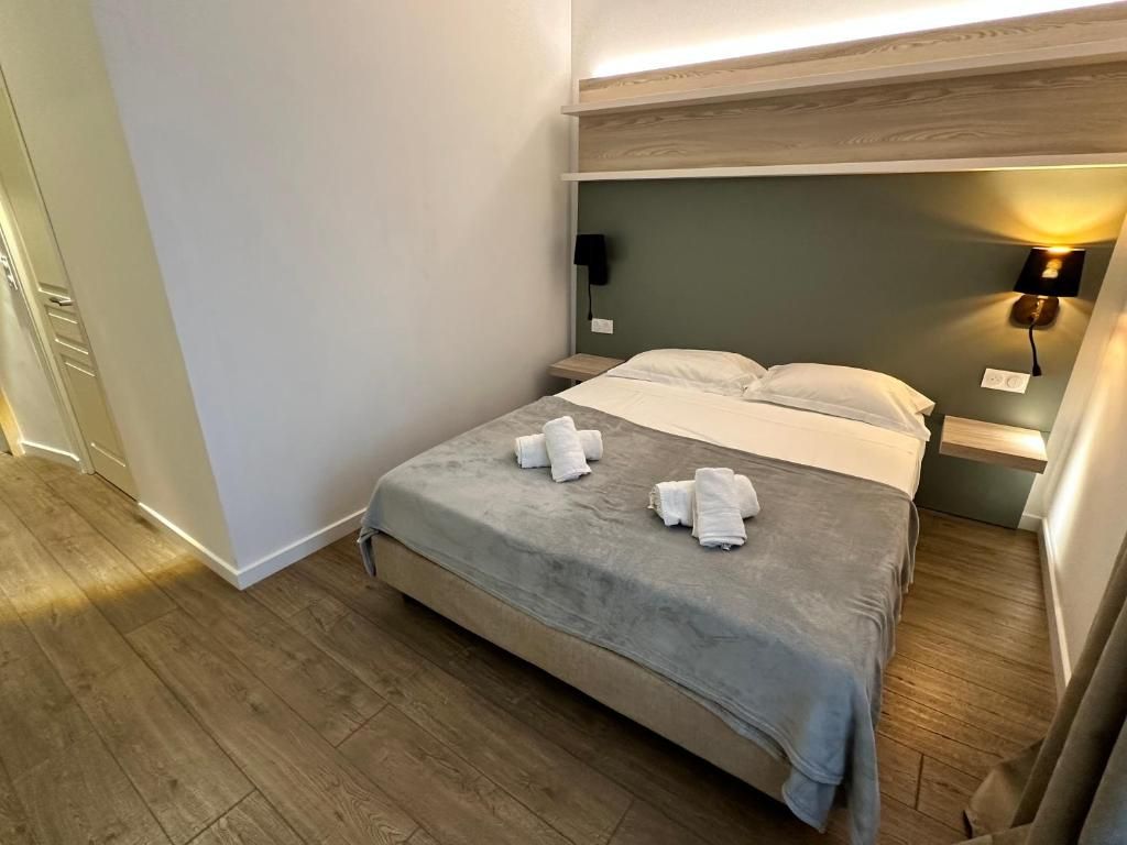 Una habitación de hotel con una cama, dos lámparas de noche y una mesita de noche.