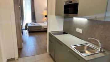Une cuisine compacte dotée d’un four encastré, d’un évier et d’un petit plan de travail.