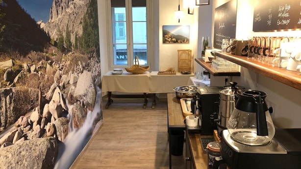 Un coin cuisine accueillant, agrémenté d’une fresque murale représentant une cascade de pierres, d’une table en bois et d’une machine à café.