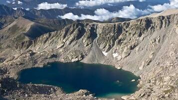 Un paysage montagneux avec un lac d’un bleu profond, entouré d’un terrain rocheux.