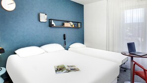 Una habitación de hotel con una cama grande, un escritorio con una computadora portátil, un teléfono, un reloj y una ventana con cortinas.