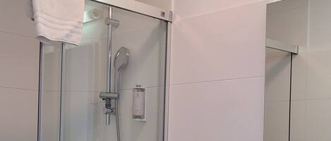 A modern bathroom with a glass shower enclosure, a wooden vanity with a sink, and a mirror above the vanity.