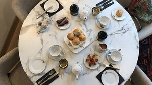 Ein runder Marmor-Tisch, gedeckt für eine Mahlzeit, mit Tellern, Tassen und einer Teekanne.