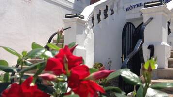 Un edificio blanco con un letrero que dice "H. DE LA F." y "HOTEL" sobre la entrada.