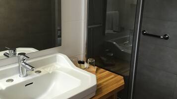 Een badkamer met een wit wastafelmeubel, een spiegel en een douchecabine van glas.