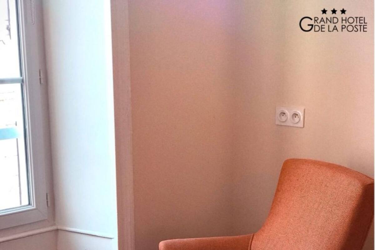 Una habitación de hotel con una cama, una pila de toallas blancas y una silla naranja.