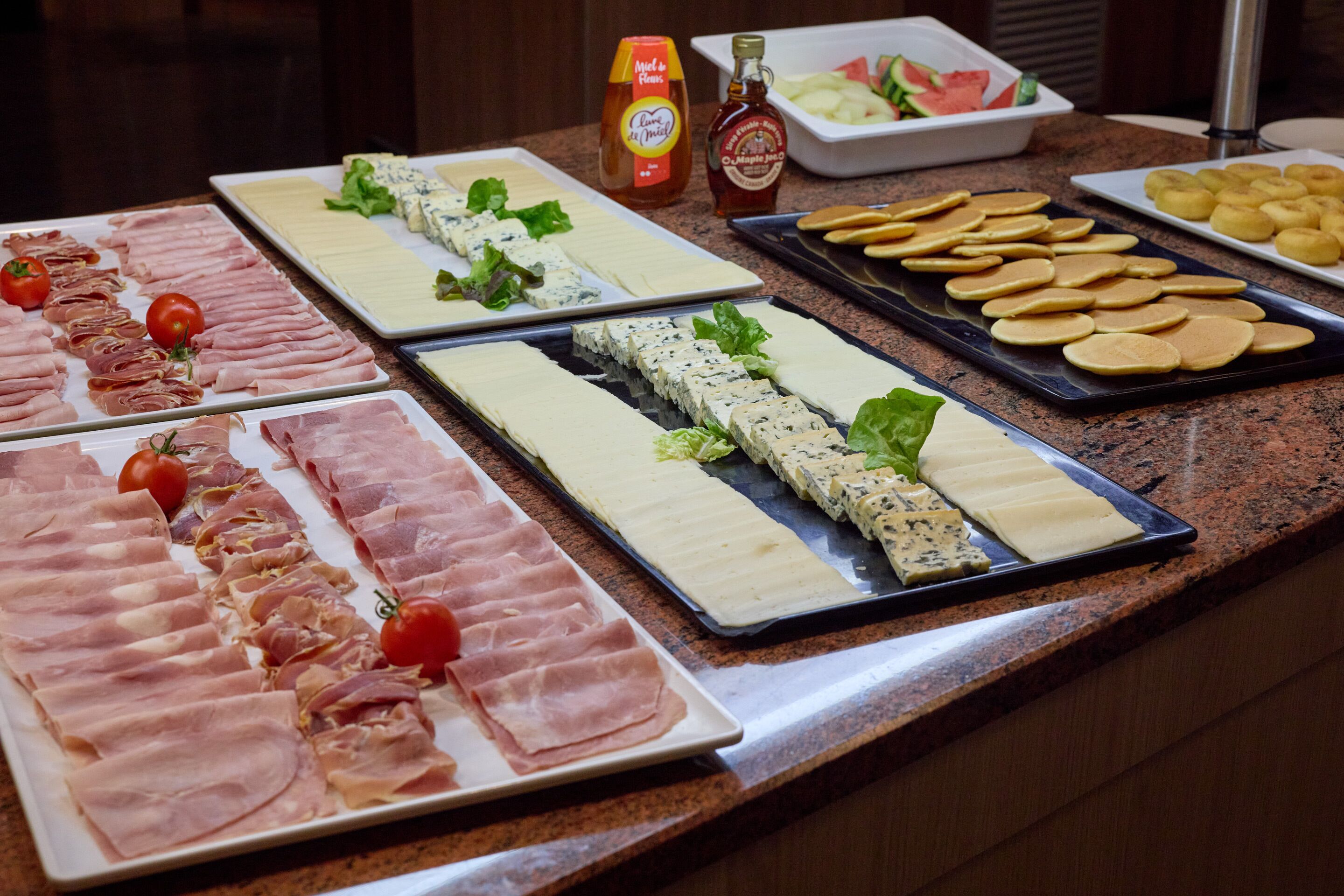 Un buffet proposant une variété de plats, notamment des viandes, des fromages et des crackers.