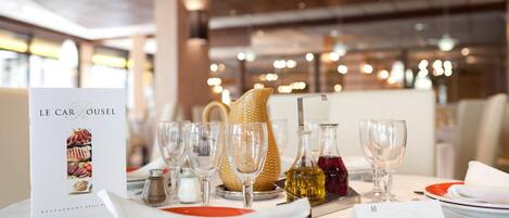 Un ambiente de restaurante con un menú, copas de vino y una botella de vino tinto sobre la mesa.