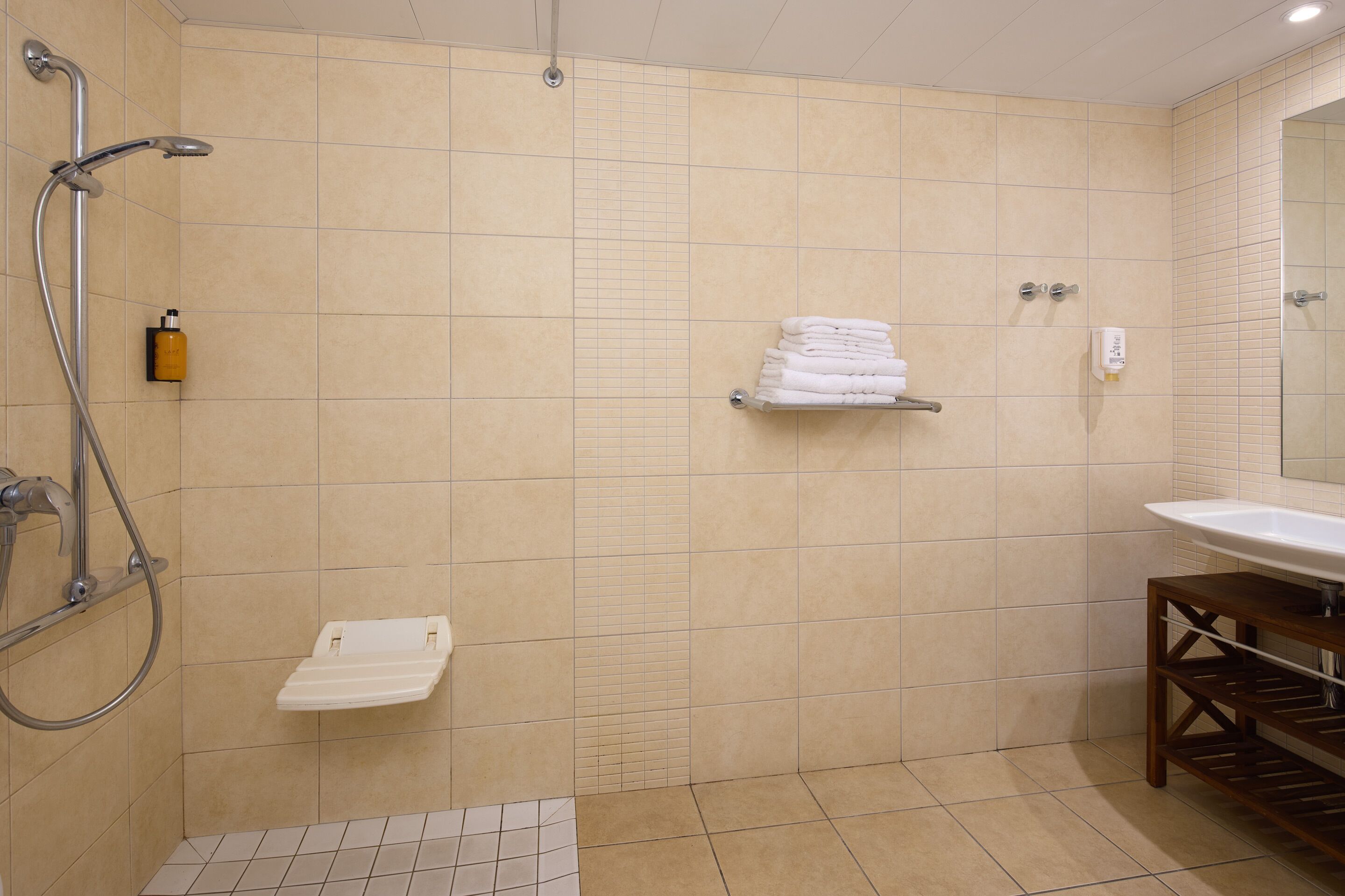 A bathroom with a shower, a sink, and a towel rack.