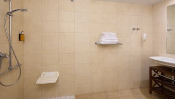 A bathroom with a shower, a sink, and a towel rack.