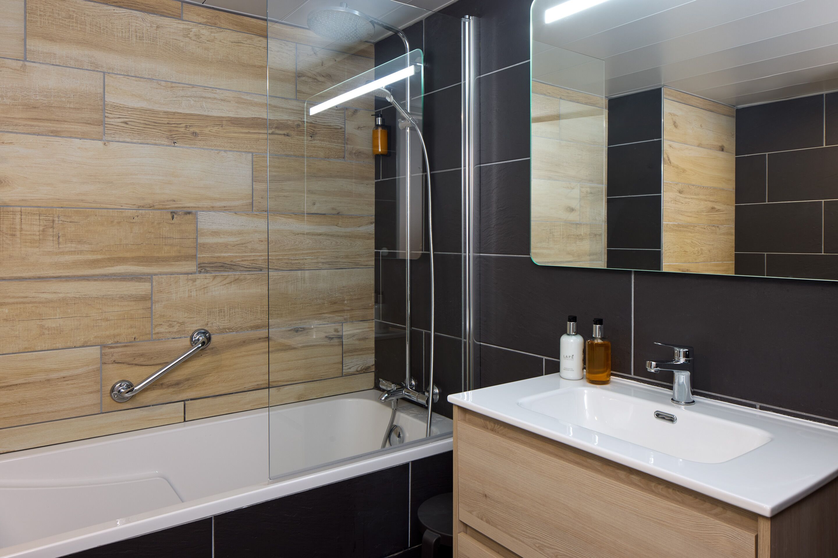A modern bathroom with a bathtub, a vanity with a sink, and a mirror.
