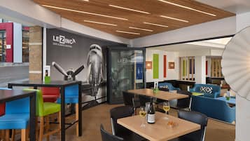 Ein modernes Café mit Holzbodenpaneelen, bunten Stühlen und einem gut sichtbaren LEZINC-Logo an der Wand.
