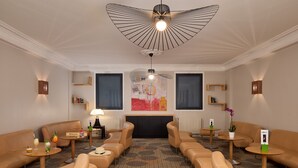 A hotel lobby with leather sofas, a fireplace, and a large abstract painting on the wall. - Hotel Roissy Lourdes (Lourdes)