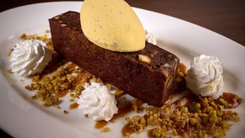 Ein Dessert mit einer Kugel Eis, umgeben von Schlagsahne und zerbröselten Nüssen.