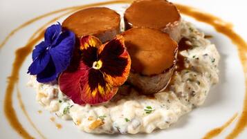 Une assiette de dessert avec une crème pâtissière, une base crémeuse, et des fleurs décoratives.