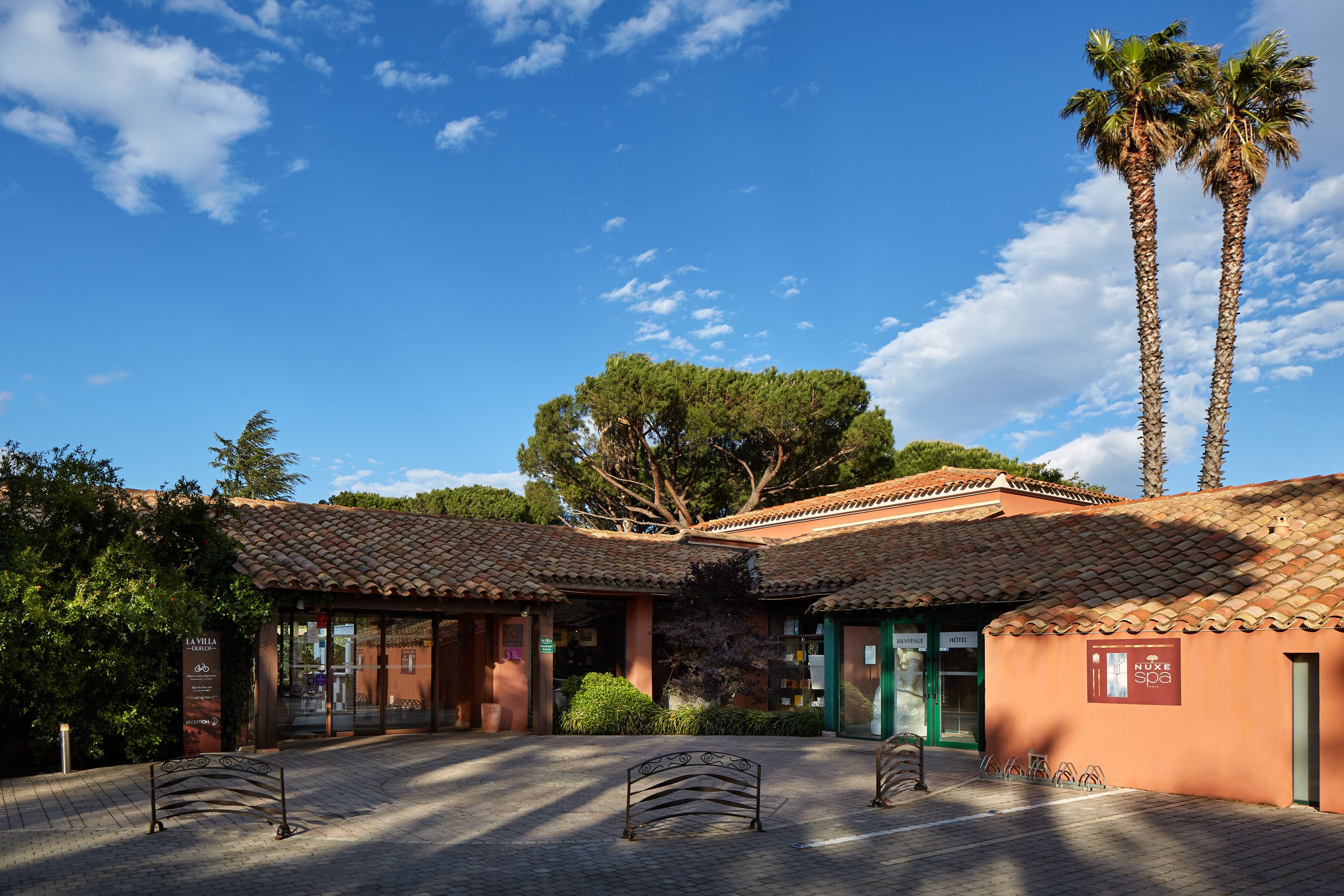 Un pati amb teulada, bancs i palmeres.
